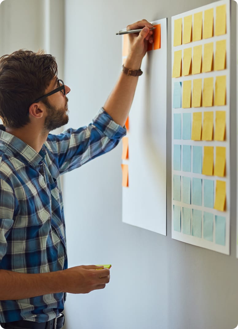 close-up of gentleman writing sticky notes on white board